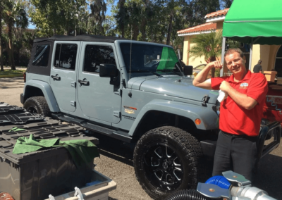 employee showing his strength to clean gray jeep