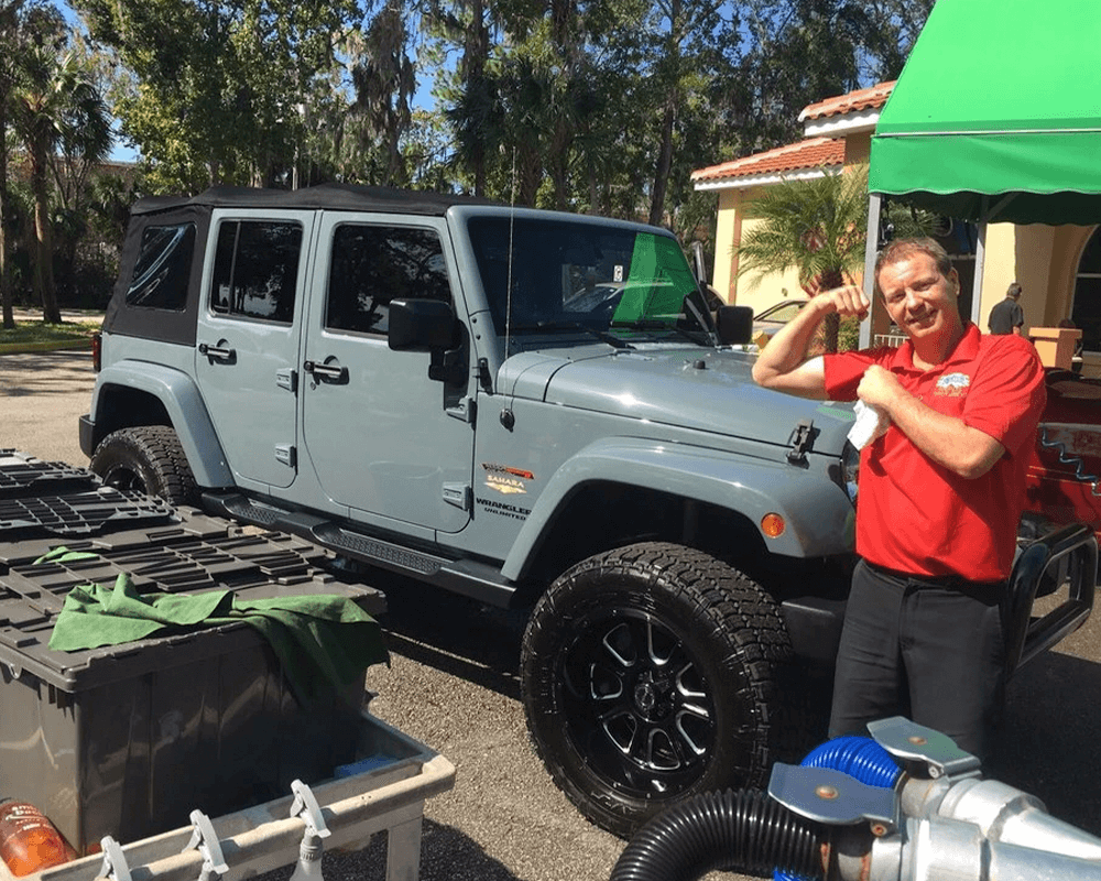 employee showing his strength to clean gray jeep